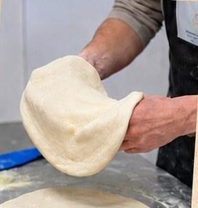 מתיחת בצק פיצה בעבודת יד בסדנה